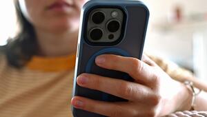 Eine junge Frau sitzt mit ihrem Smartphone auf dem Sofa