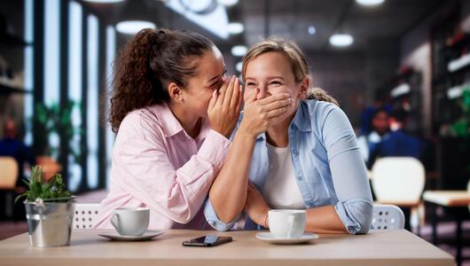 Junge Frauen lachen im Café und Flüstern