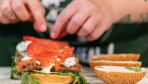 Eine Köchin belegt einen Burger mit veganem Fischersatz