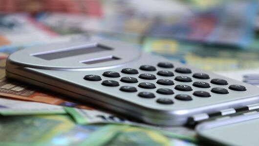 Ein Taschenrechner liegt auf verschiedenen Euro-Banknoten.