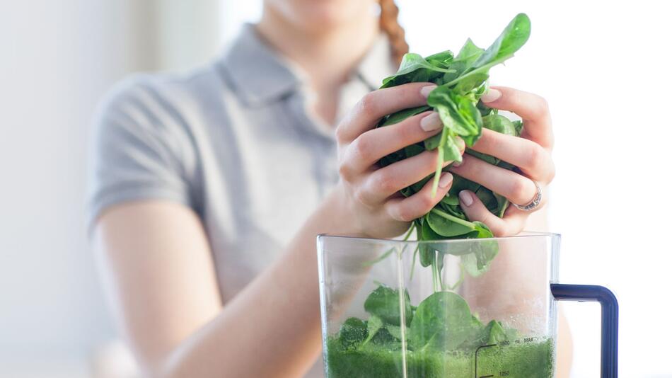 Frau bereitet am Standmixer einen Smoothie zu