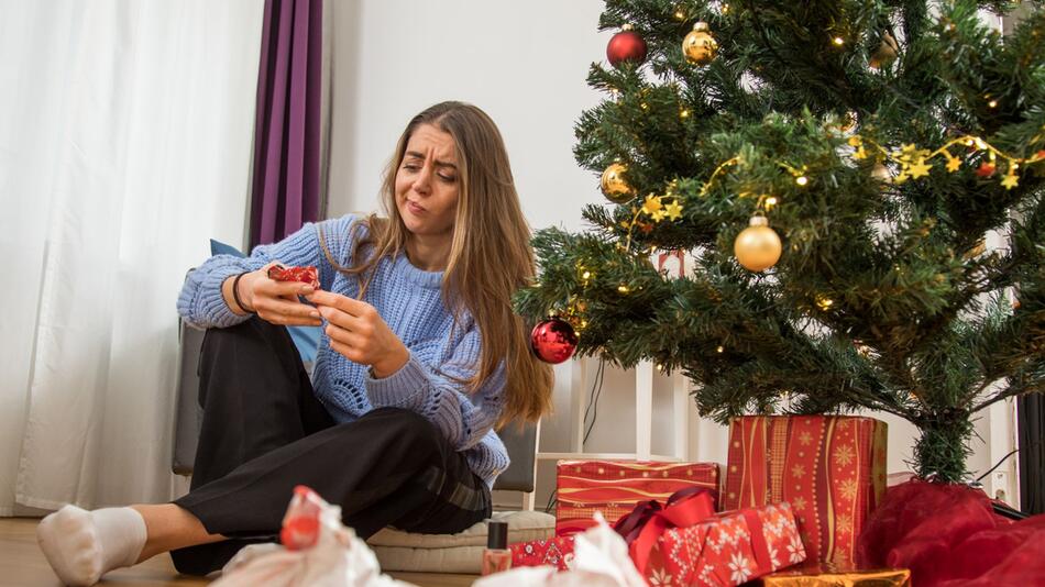 Eine Frau packt ein Weihnachtsgeschenk aus