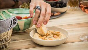 Ein Mann dippt ein Stück Brot in Hummus