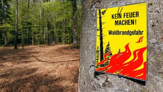 Ein Schild im Wald weist auf die Waldbrandgefahr hin