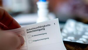 Eine Person hält eine Arbeitsunfähigkeitsbescheinigung