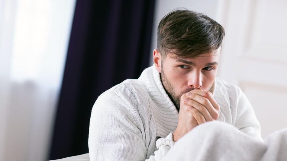 Mann fröstelt in einer Wohnung