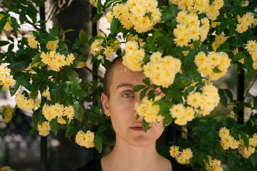 Eine Junge Frau hinter Blumen im Park