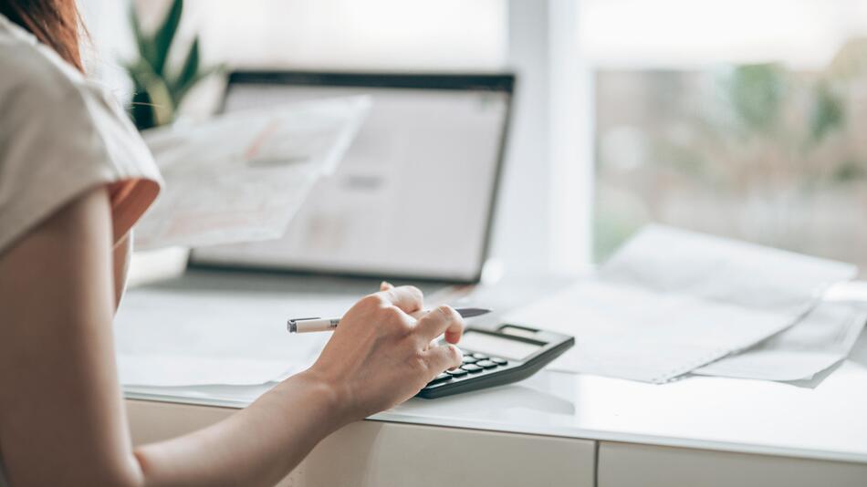 Frau mit Laptop und Taschenrechner