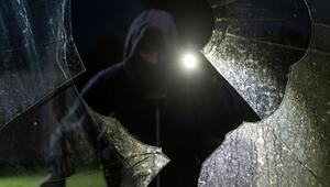 Durch eine eingeschlagene Scheibe blickt ein fiktiver Einbrecher