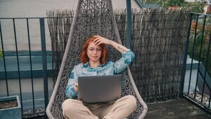 Eine Frau sitzt in einem Hängesessel und arbeitet am Laptop