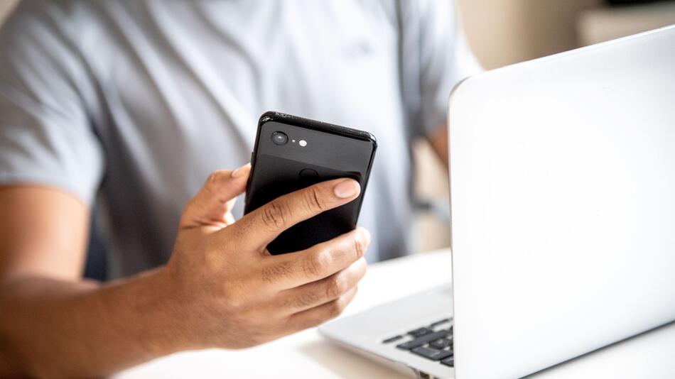Mann mit Smartphone und Laptop