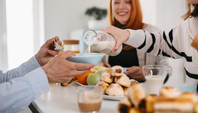 Eine Frau giesst einem Mann Milch in die Müslischüssel