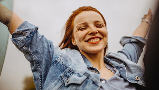Frau, die sehr euphorisch die Arme hochwirft. 