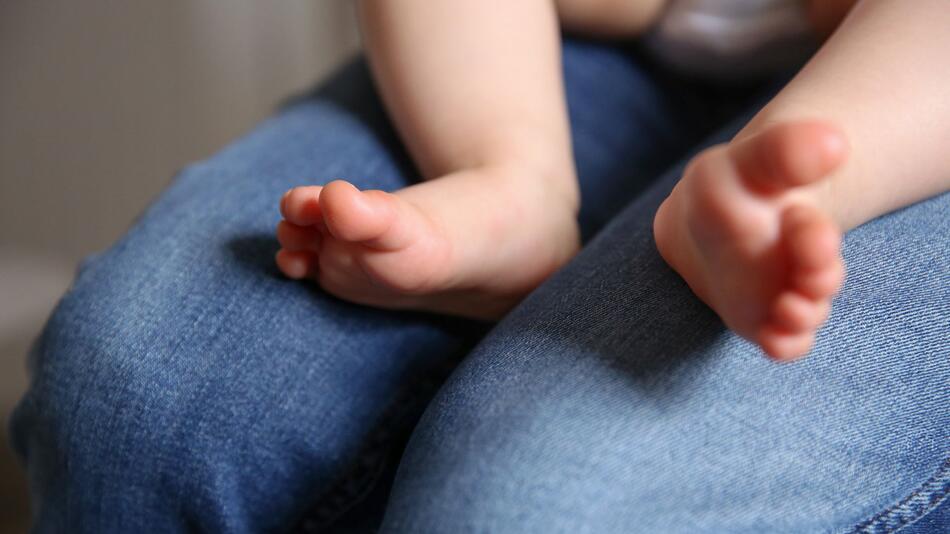 Baby sitzt auf dem Schoss einer Frau