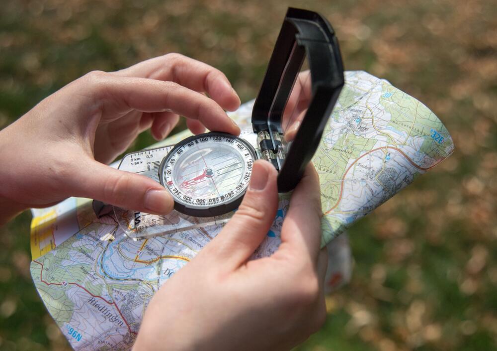 Eine Frau benutzt einen Kompass und eine Wanderkarte