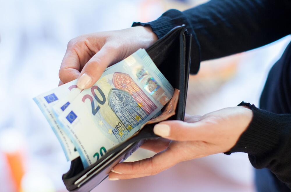 Eine Frau holt Geldscheine aus ihrer Geldbörse