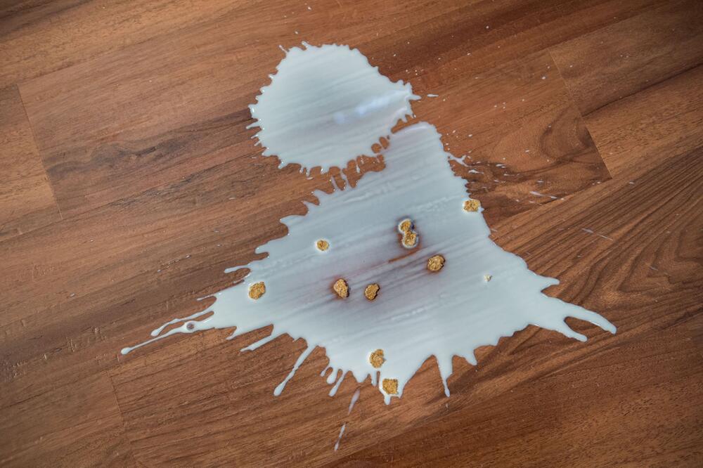 Ausgeschüttete Milch mit Cornflakes auf einem Fussboden