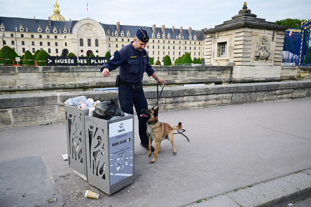 Ein Polizist mit einem Hund an einem Mülleimer in Paris