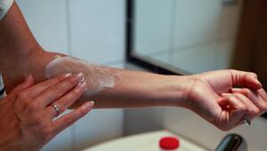 Frau cremt sich einen Arm ein
