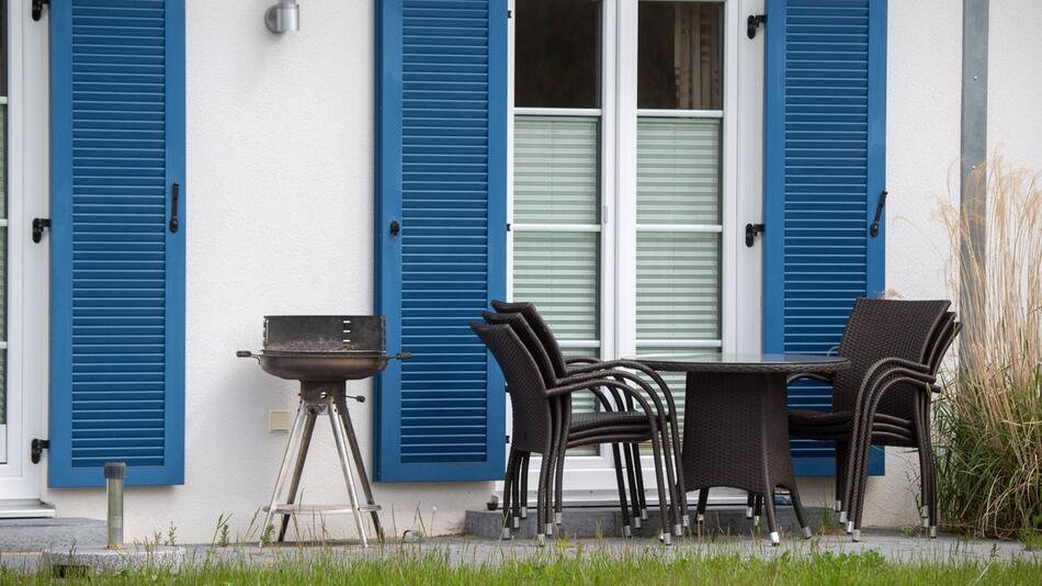 Gartenmöbel und ein Grill stehen auf der Terrasse vor einem Haus