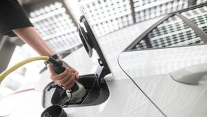 Frau steckt einen Ladestecker für ein E-Auto in eine Buchse