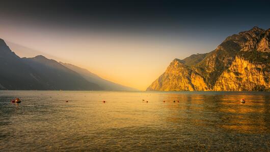 Familie sitzt am Pier in Malcesine und blickt auf den Gardasee.