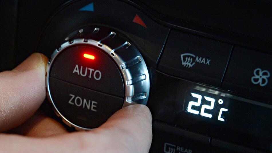 Ein Mann dreht an dem Einstellrad für die Klimaanlage im Auto