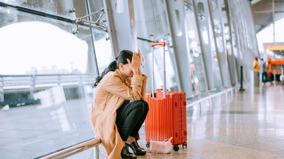 Eine Frau kniet verzweifelt am Flughafen