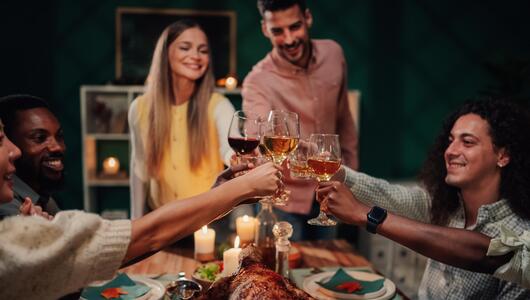 Gruppe Freunde stosst beim winterlichen Essen mit Wein an