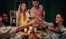 Gruppe Freunde stosst beim winterlichen Essen mit Wein an