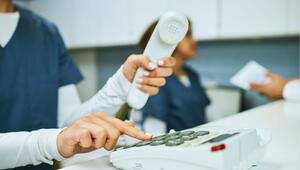 Frau am Empfang einer Arztpraxis, die ein Telefon bedient. 