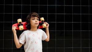 Selbstbewusster Junge trägt ein Skateboard auf seinen Schultern