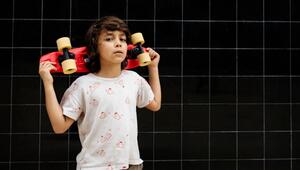 Selbstbewusster Junge trägt ein Skateboard auf seinen Schultern