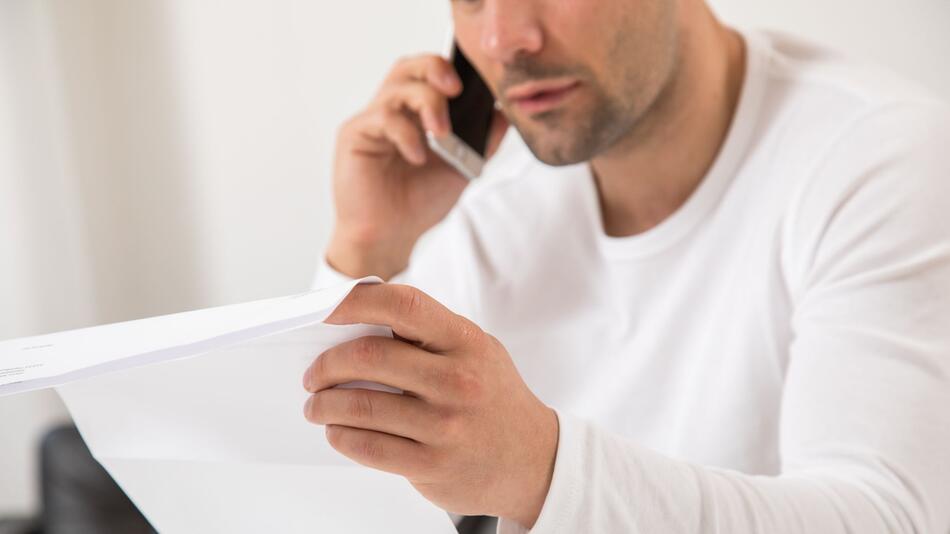 Ein Mann telefoniert und hält einen Brief in der Hand
