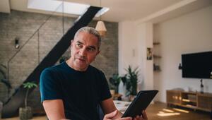 Ein Mann sitzt mit einem Tablet am Tisch