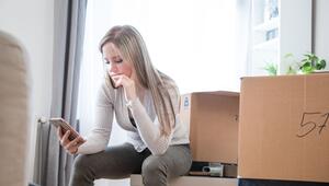 Eine Frau sieht zwischen Umzugskartons auf ein Handy