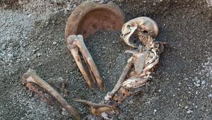 Skelett, teils mit Asche bedeckt, und Tongefäss