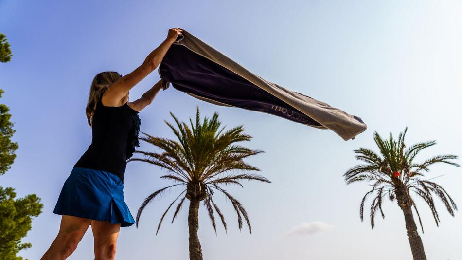 Frau breitet am Strand von Alcudia ihr Handtuch aus