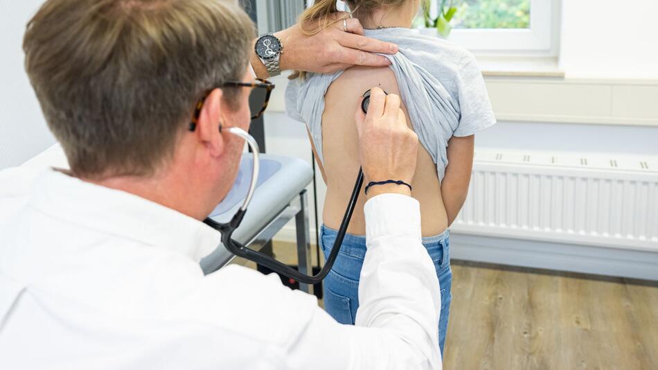 Arzt horcht mit einem Stethoskop die Atemwege eines Kindes ab