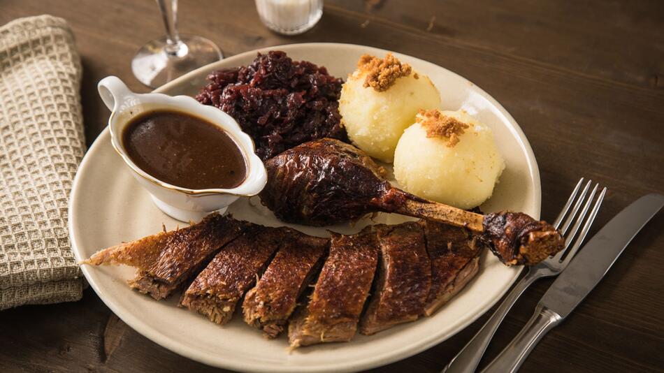 Gans wird mit Rotkohl, Klössen und Sauce serviert