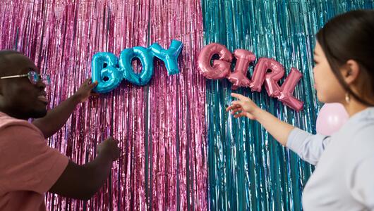 Gender Reveal Vorhang mit jungem Paar davor. 