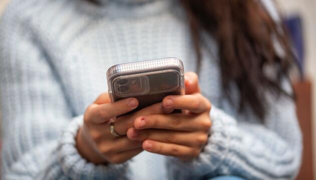 Eine junge Frau hält ein Smartphone in den Händen