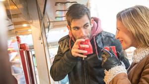 Ein Mann und eine Frau trinken Heissgetränk auf Weihnachtsmarkt