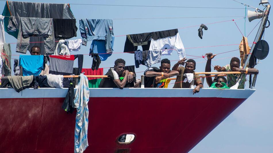 Migranten stehen an Bord eines Schiffes