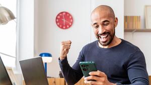 Ein Mann schaut auf sein Handy und freut sich.