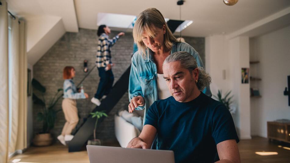 Ein Mann und eine Frau blicken auf einen Laptop