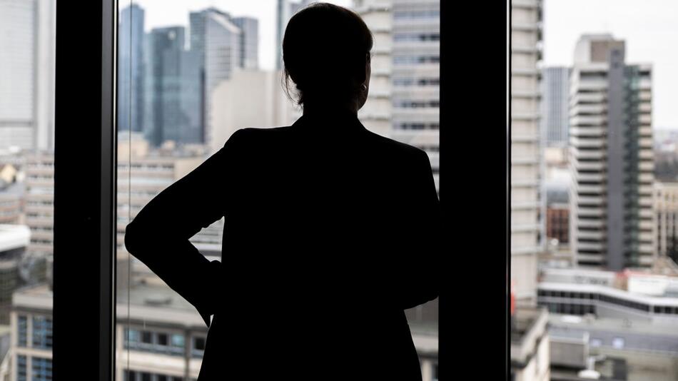 Frau schaut aus einem Bürofenster