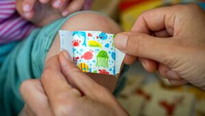 Eine Mutter klebt ihrer Tochter ein buntes Pflaster aufs Knie