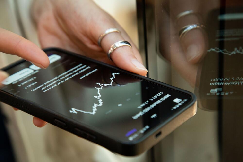 Eine Frau schaut auf dem Handy nach einem ETF Kurs