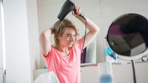Eine junge Frau föhnt ihre Haare